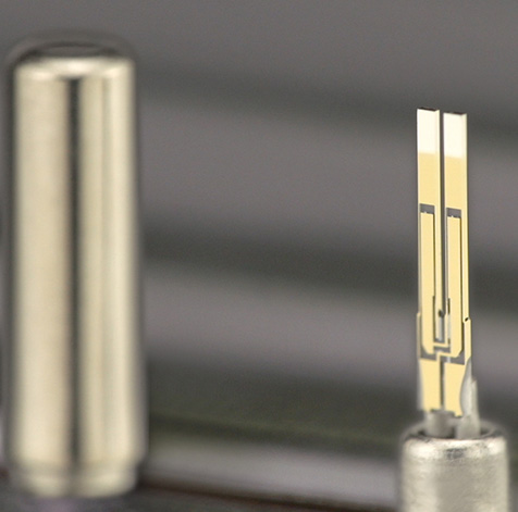 El oscilador de cristal de cuarzo con forma de horquilla se ajusta en una caja de 1 mm de diámetro.