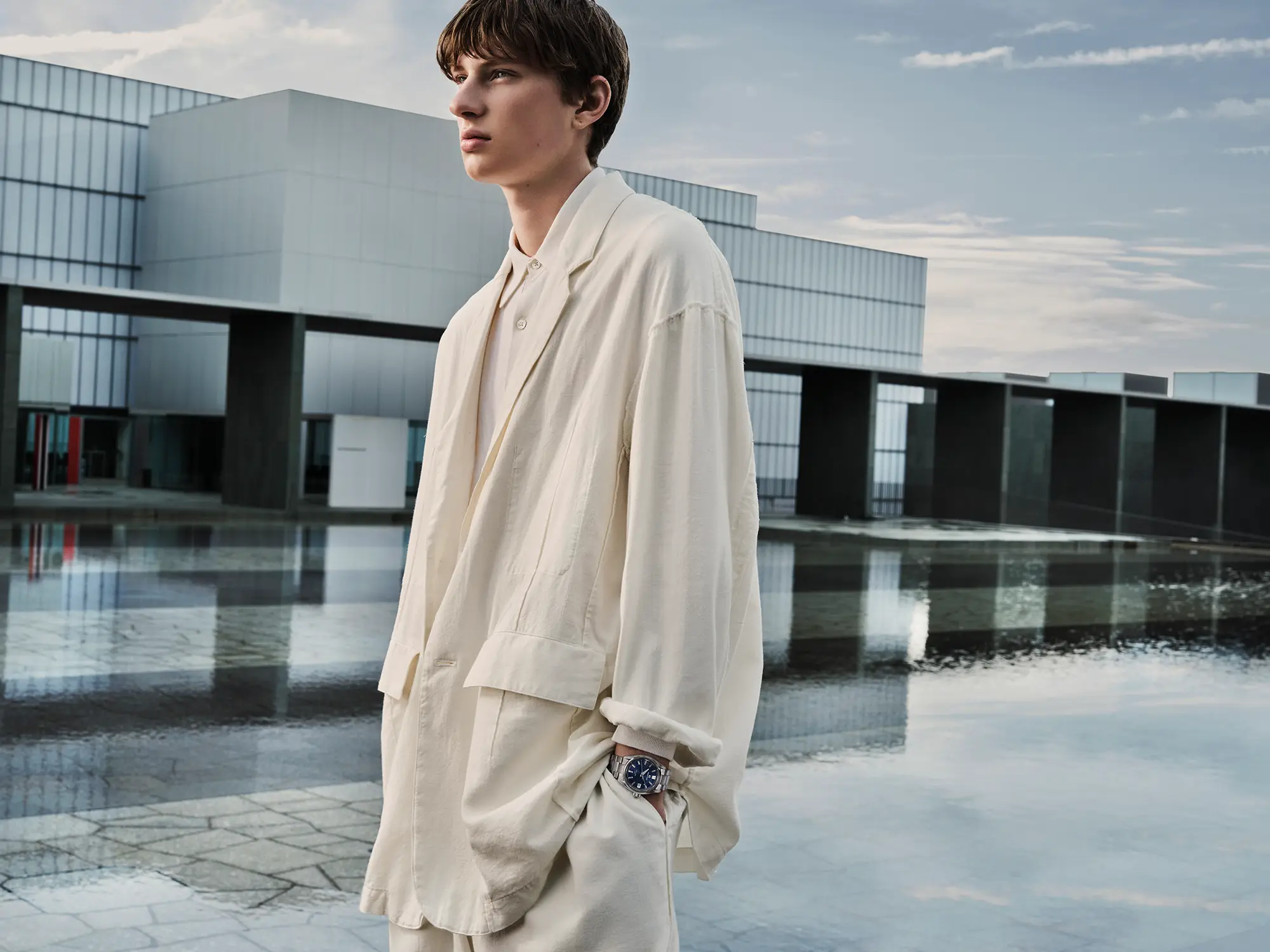 A visual capturing a model wearing the GRAND SEIKO watch SLGB013 in front of a piece of famous architecture, with the theme of LIGHT & SHADOW.
